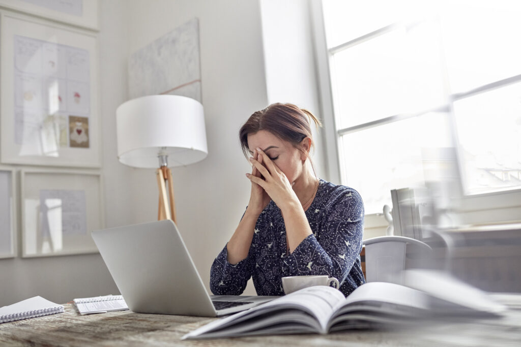 Κουρασμένη, στρεσαρισμένη επιχειρηματίας στο φορητό υπολογιστή με το κεφάλι στα χέρια