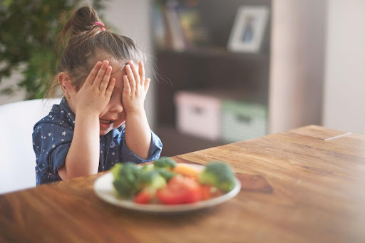 Κορίτσι που κλείνει τα μάτια σε φρούτα. Ένα δείγμα ότι απομακρύνονται τα παιδιά από την βιώσιμη διατροφή.